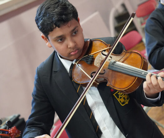 Student playing the violin with focus and concentration in a school setting.