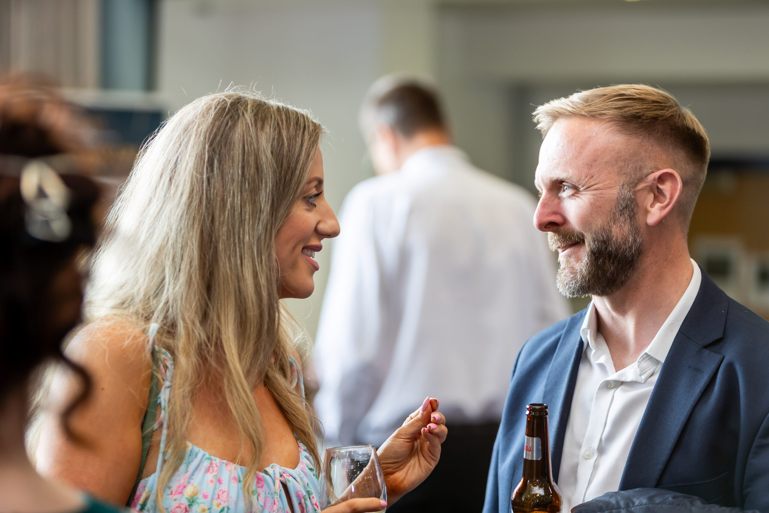 A man and woman talking to each other while having a drink in a social setting.