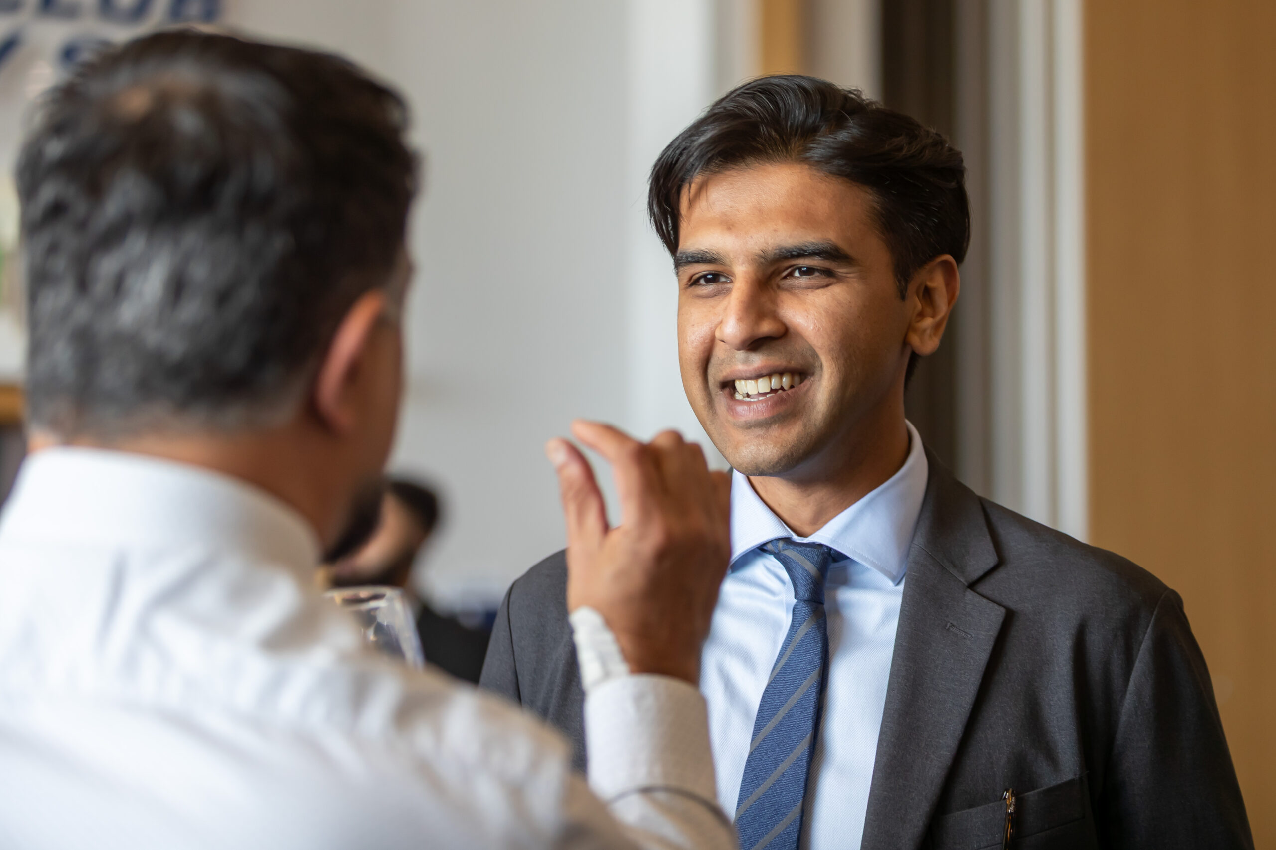 a man in a suit smiling and talking to another man