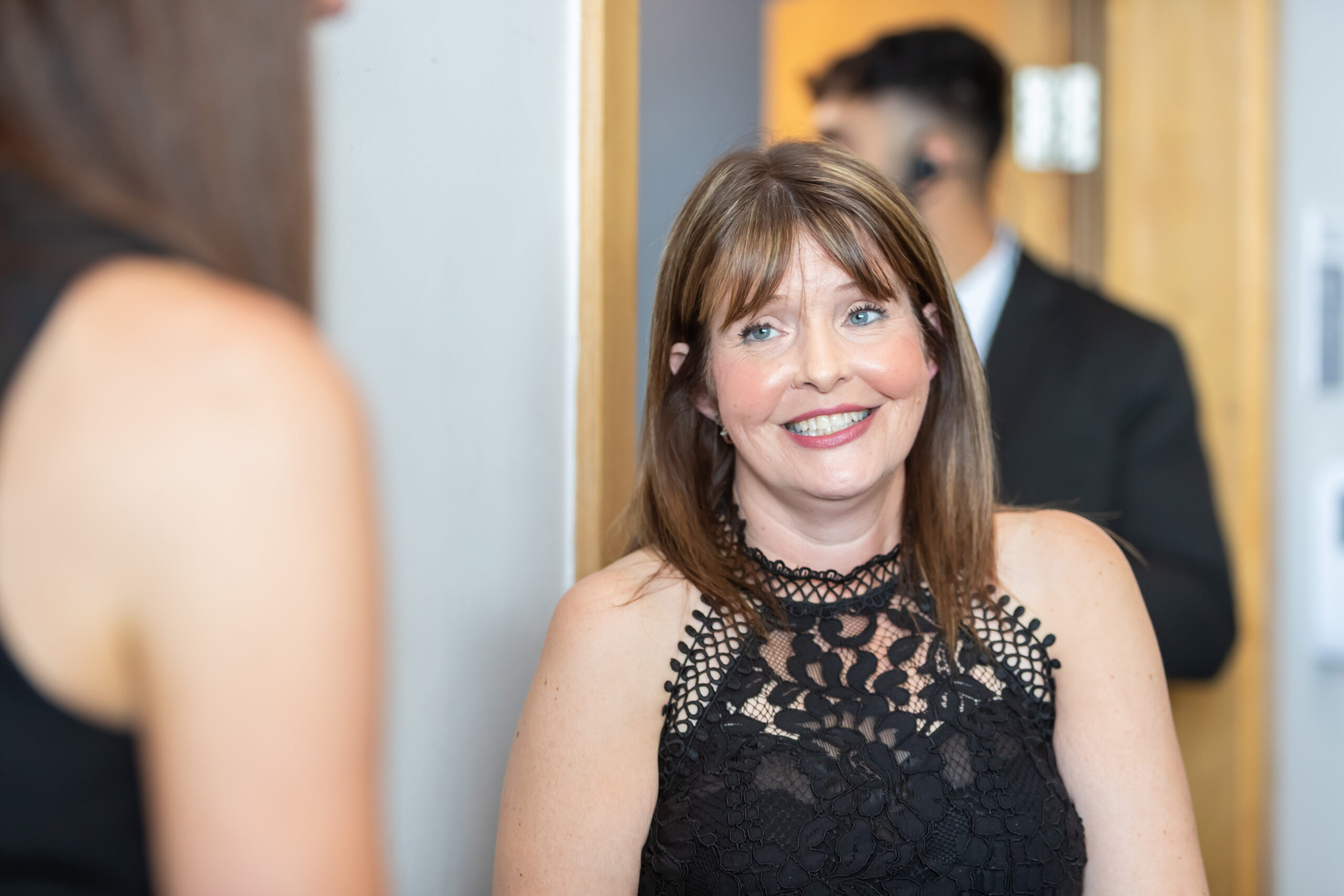 A woman in a black dress smiling at another person