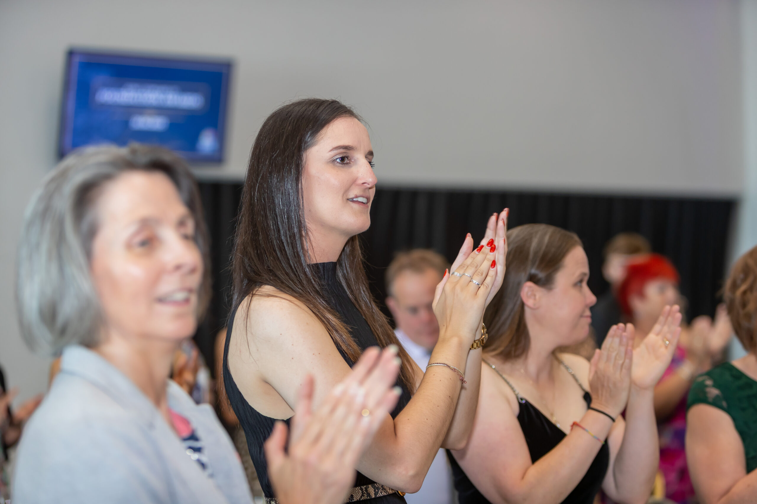 People clapping at an event, likely in a university setting.