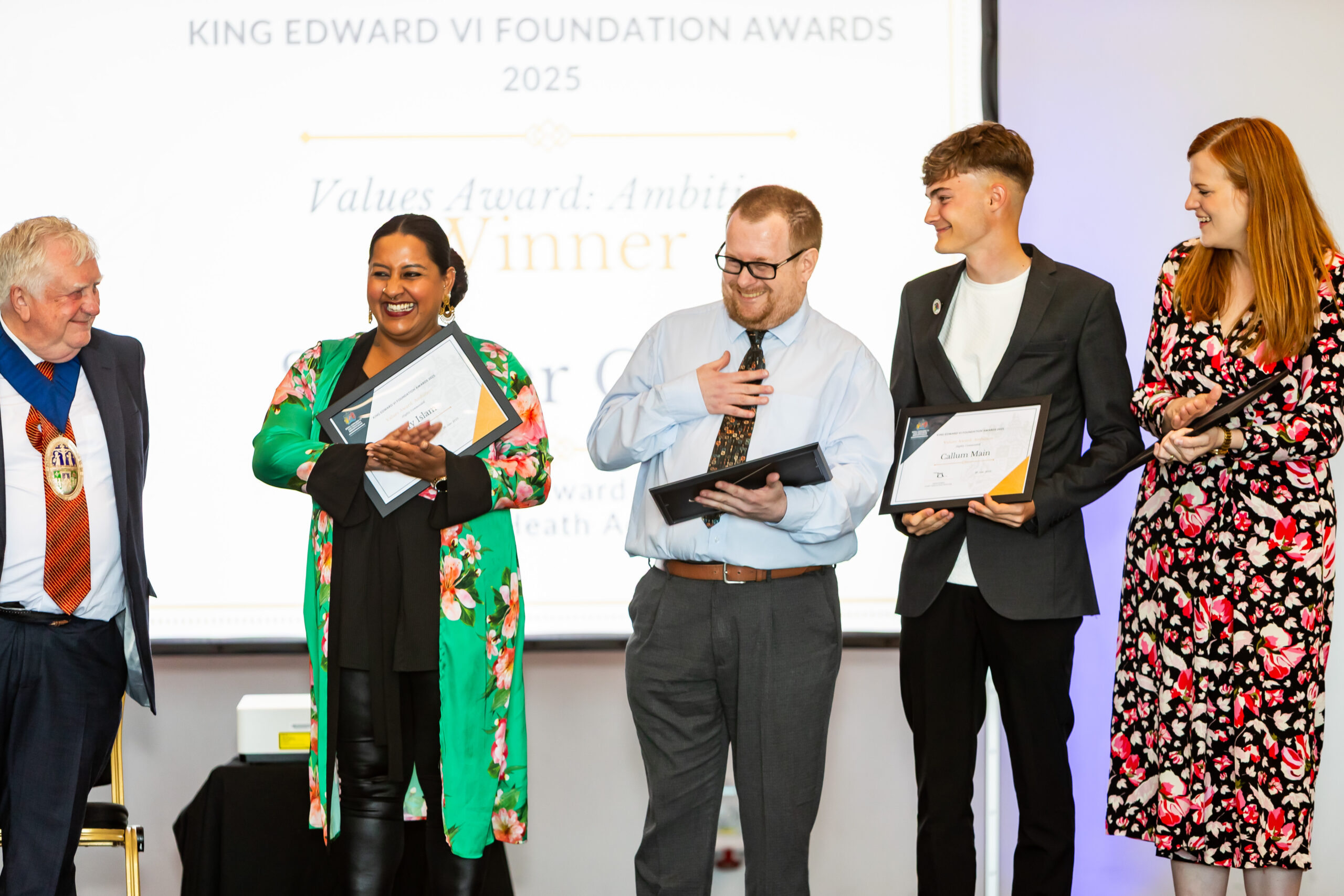 Students and adults on stage holding certificates at the King Edward VI Foundation Awards 2025.
