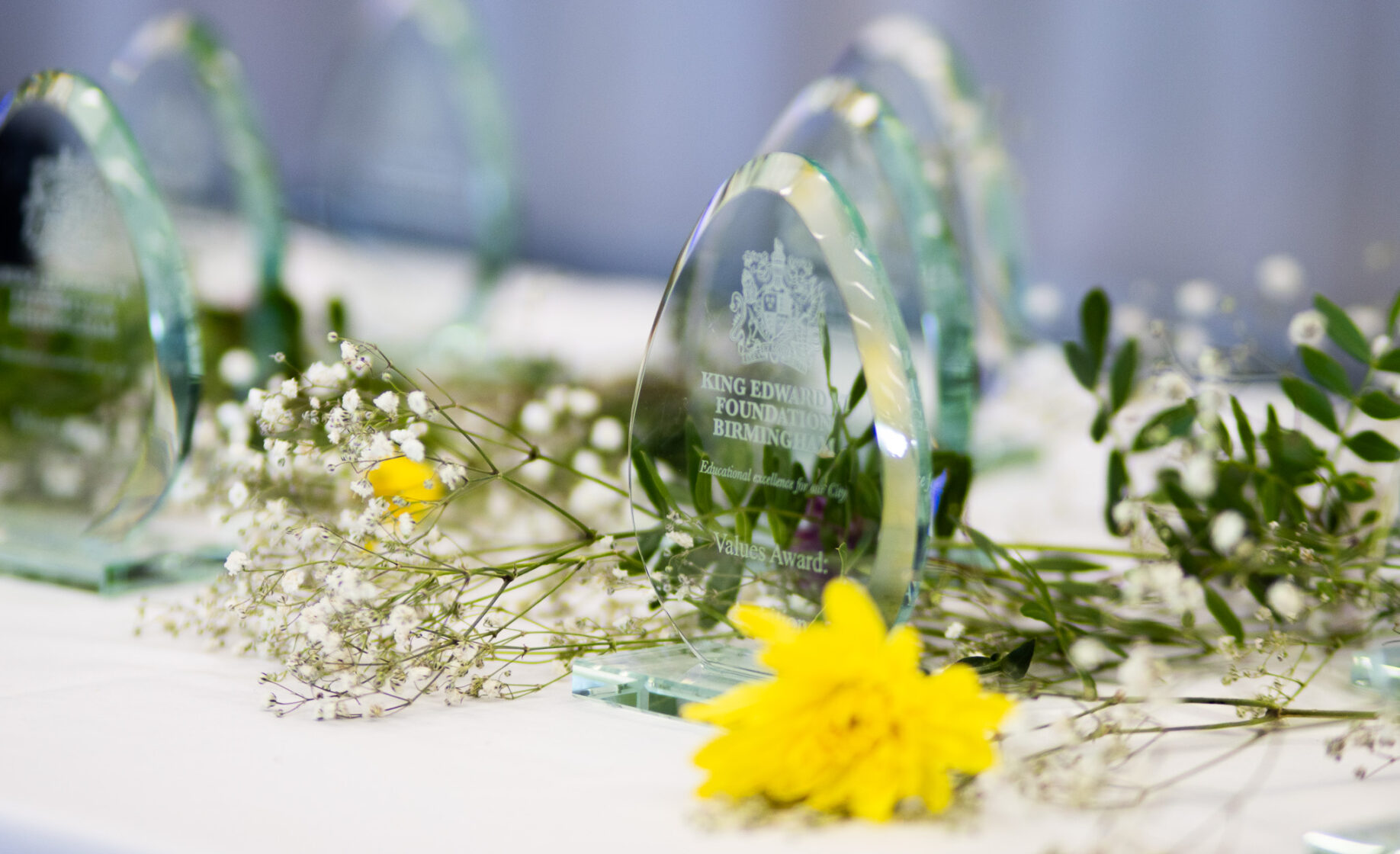 Glass awards on a table with floral decorations for an educational event
