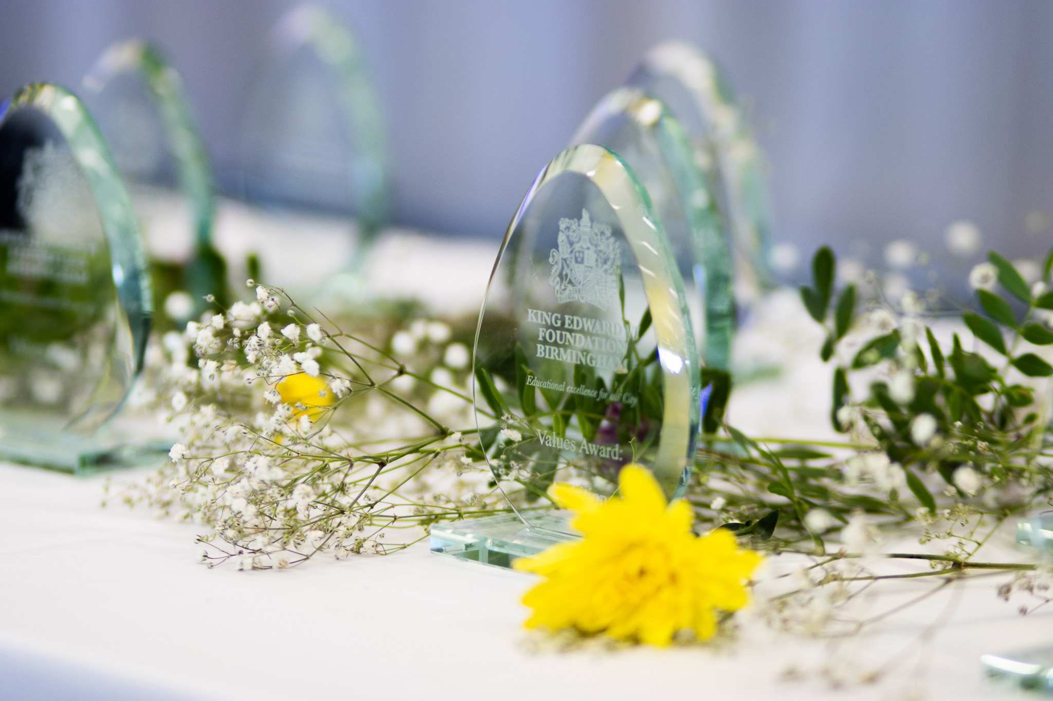 Glass awards on a table with floral decorations, symbolizing student achievements and educational excellence.