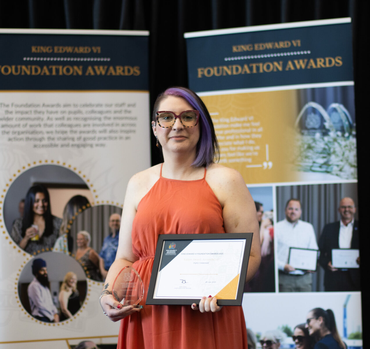 A student proudly holding an award and certificate, standing in front of banners at a Kevin Foundation event, celebrating educational achievements.