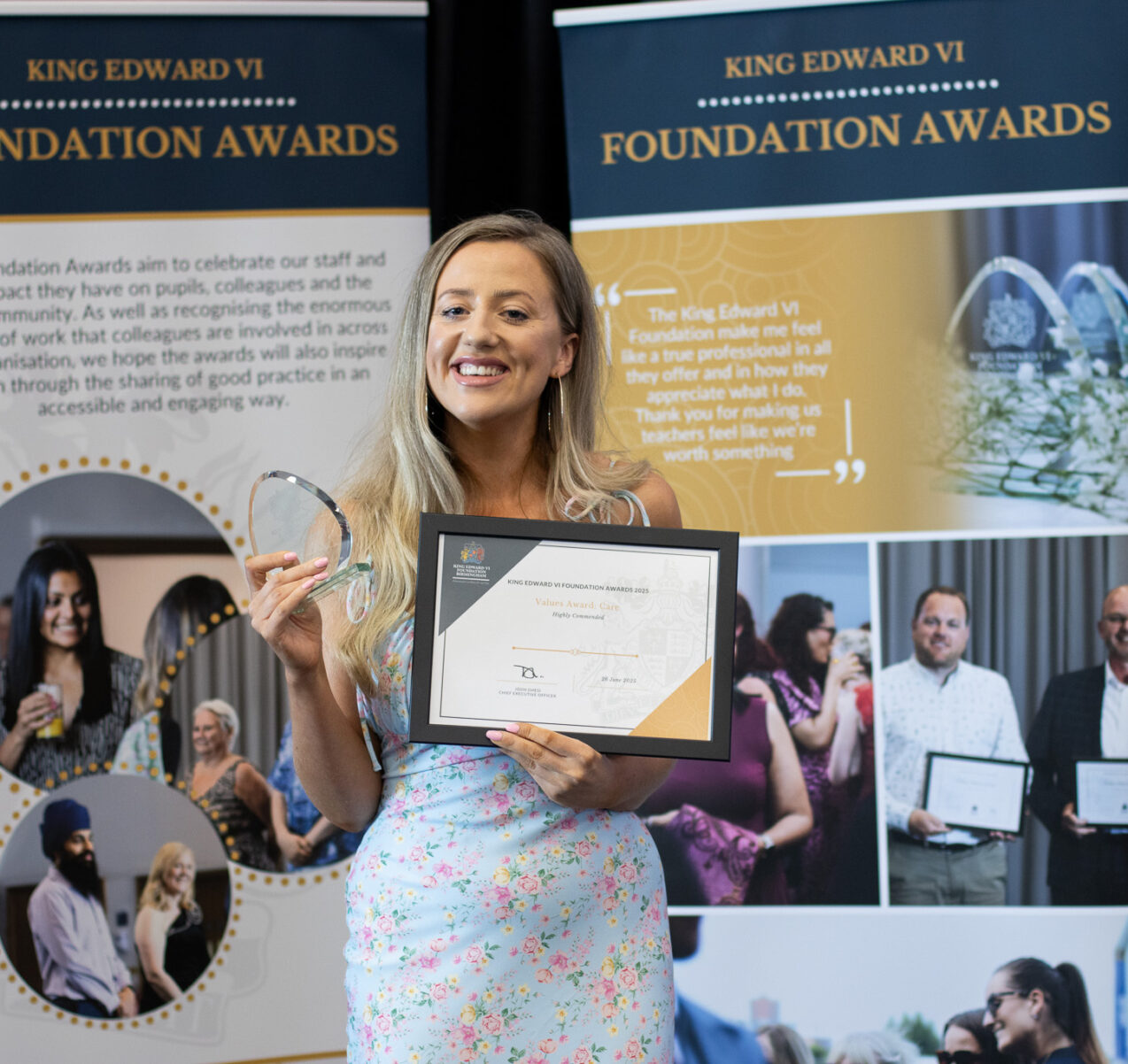 A woman proudly holds her award and certificate, standing in front of a display showcasing the King Edward's Foundation Awards, highlighting student achievements and educational excellence.