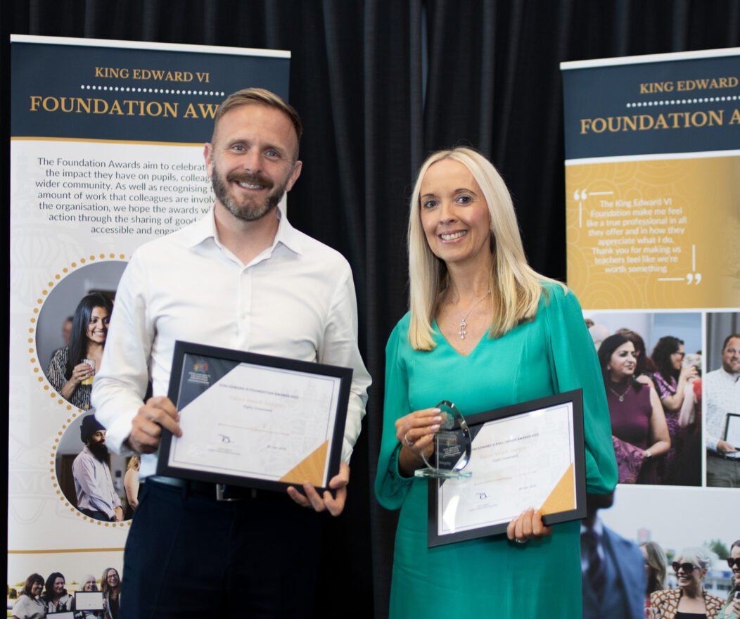 Two people proudly holding certificates in front of banners at a Kevi Foundation event, celebrating educational achievements.