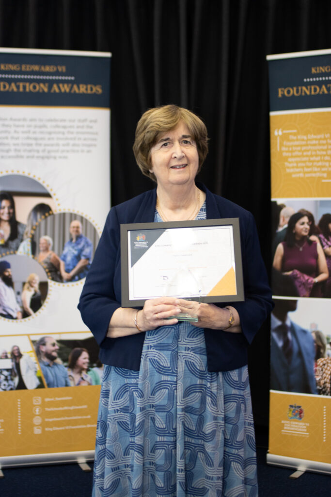Woman holding an award certificate at a Kevi Foundation event, smiling proudly.
