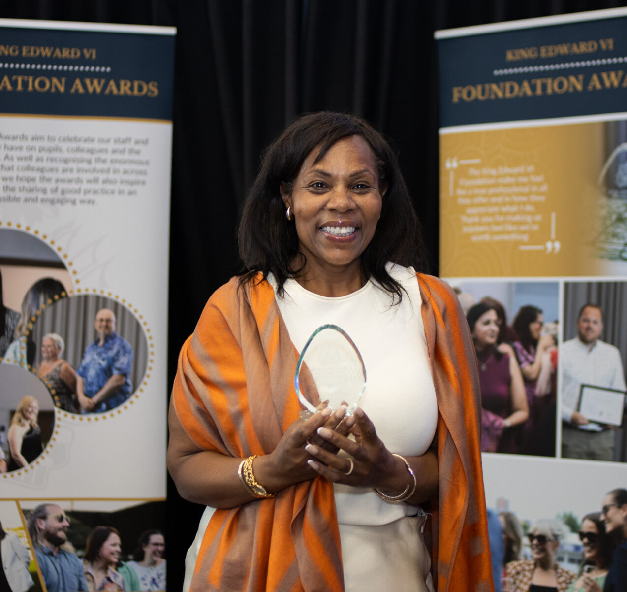 Woman holding an award at the Kevi Foundation event, standing in front of informational banners.