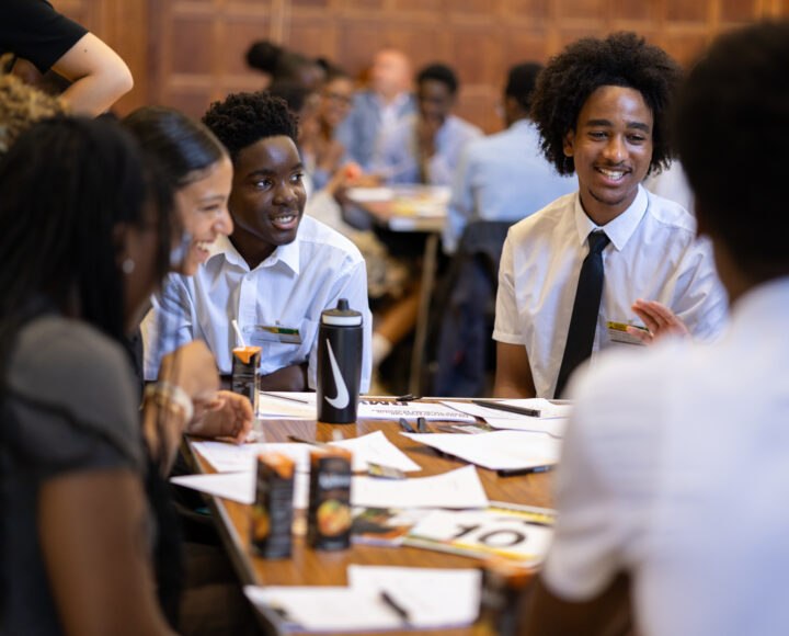 students sitting around a table in a classroom, engaged in discussion