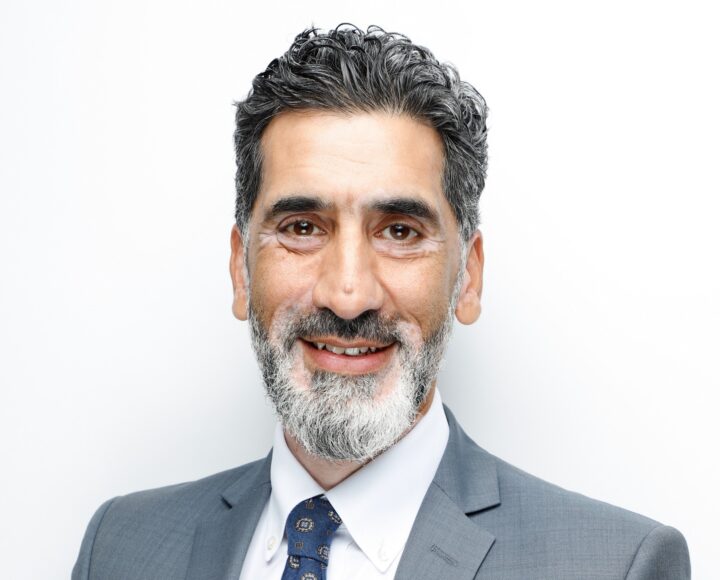 A man in a suit and tie smiling at the camera, a professional portrait
